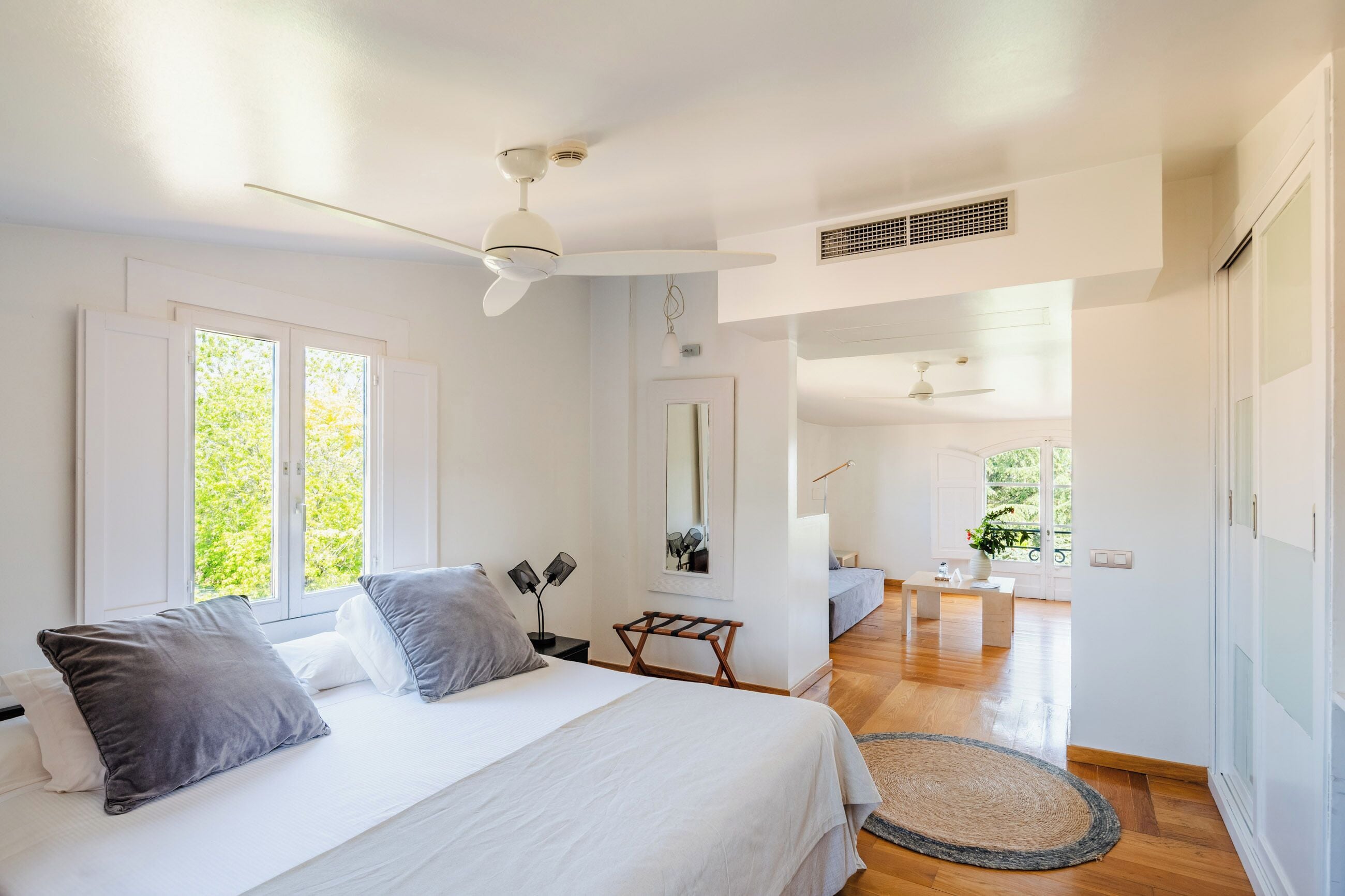 A bedroom with a bed, bedside tables, a ceiling fan, and a view of the outdoors.
