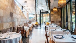 Een restaurant met ronde tafels, stoelen en hangende lampen.