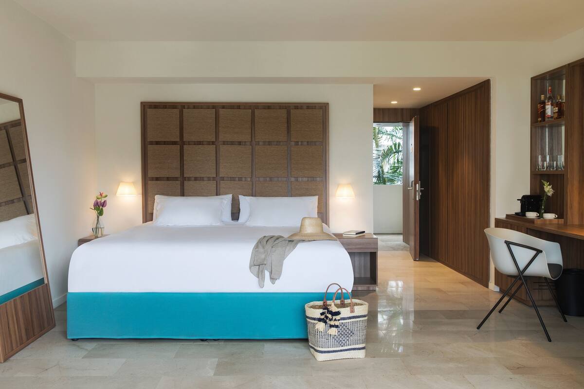 Une chambre d’hôtel moderne, dotée d’un grand lit, d’un bureau et d’un mini-bar.