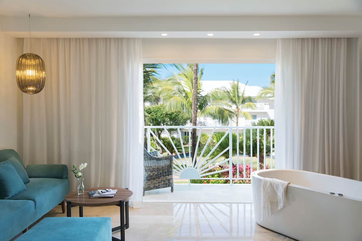 Une chambre d’hôtel moderne dotée d’un balcon, d’un canapé, d’une table basse et d’une baignoire.