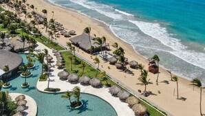 Een resort met een groot zwembad, strand en uitzicht op de oceaan.