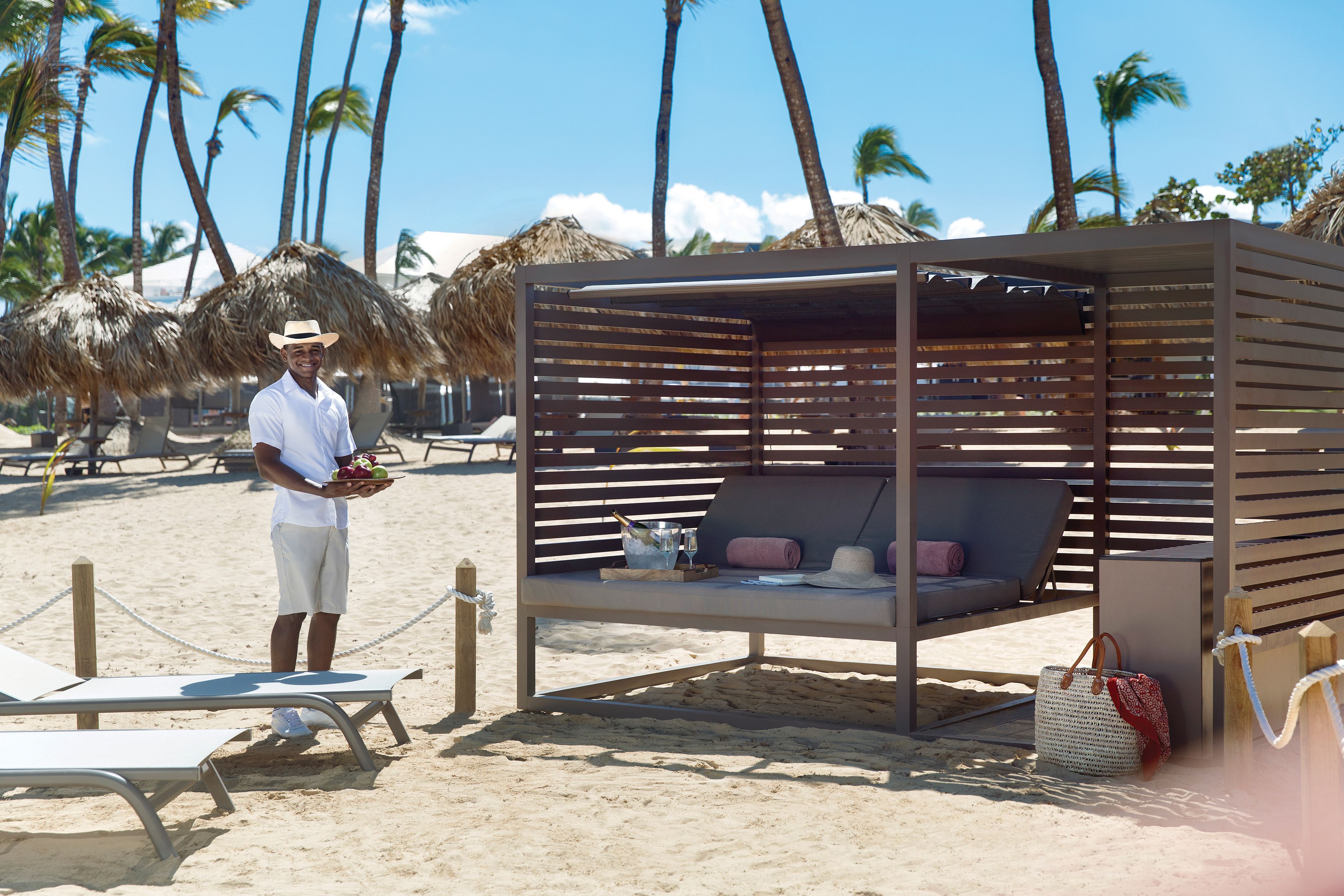 Un salón junto a la playa con estructura de madera, una mesa de billar y un sillón de playa.