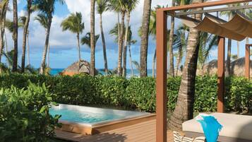 A pool area with a wooden deck, a lounge chair, and a thatched-roof structure.