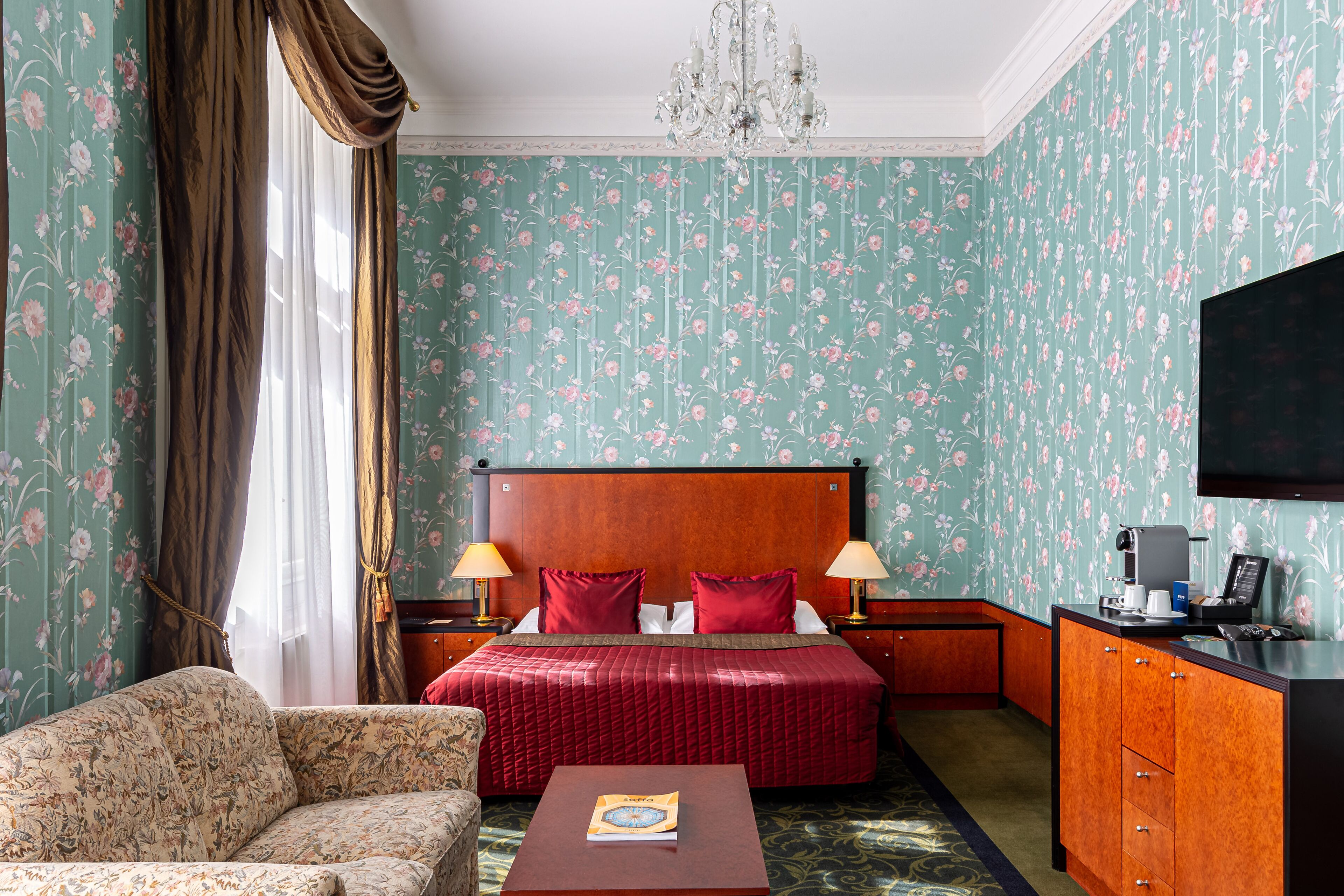 A hotel room with a bed, a sofa, a desk, and a TV.