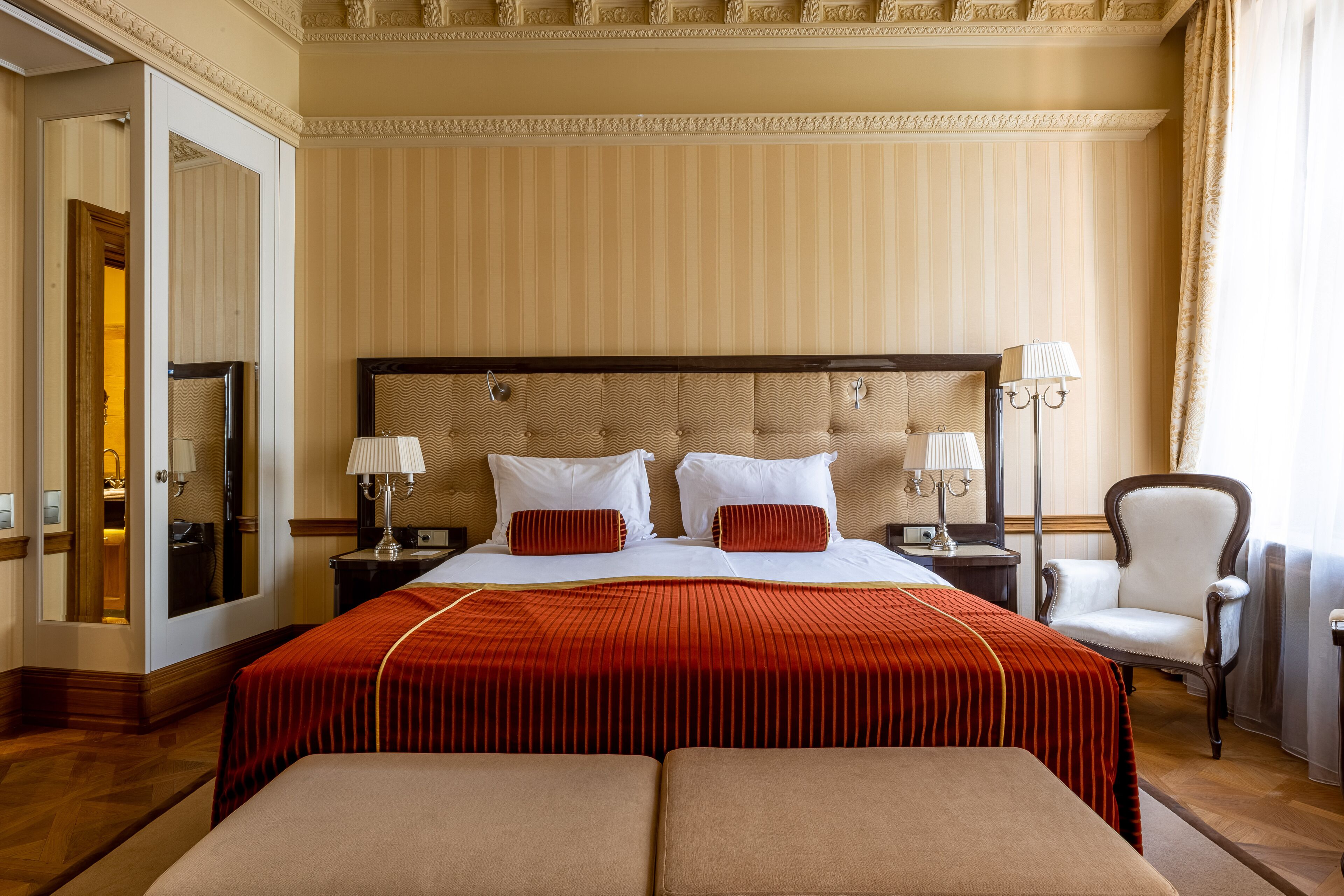 A hotel room with a large bed, two bedside tables with lamps, a chair, and a mirror.