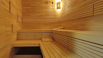 A sauna with wooden walls and benches, a small window, and a light fixture.