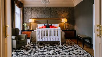 A bedroom with a crib, a bedside table with a lamp, a chair, and a bench.
