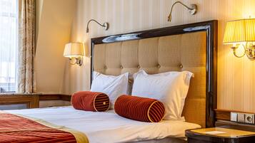 A hotel room with a large bed, striped wallpaper, and two wall-mounted lamps.