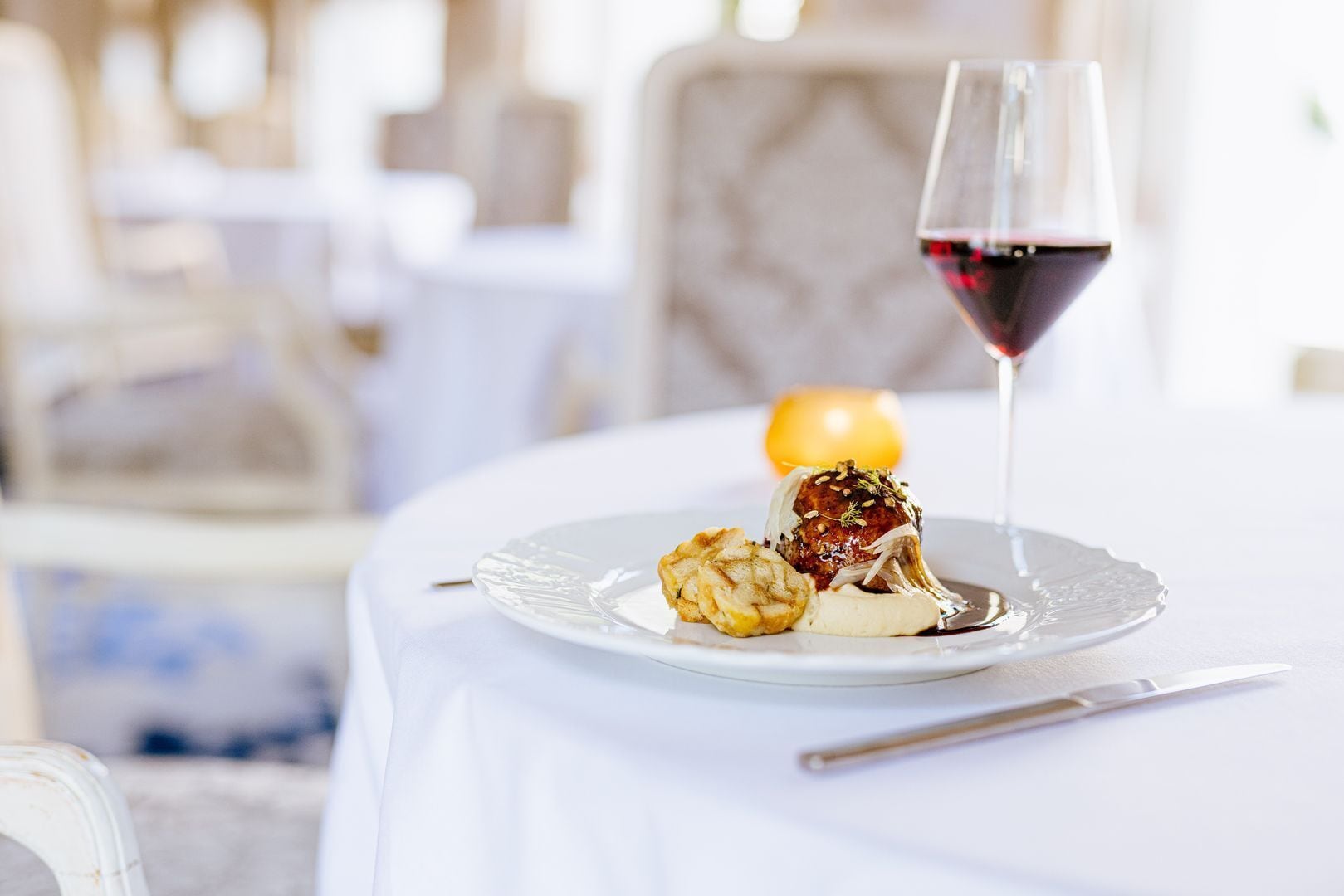 A dining table with a plate of food and a glass of red wine.