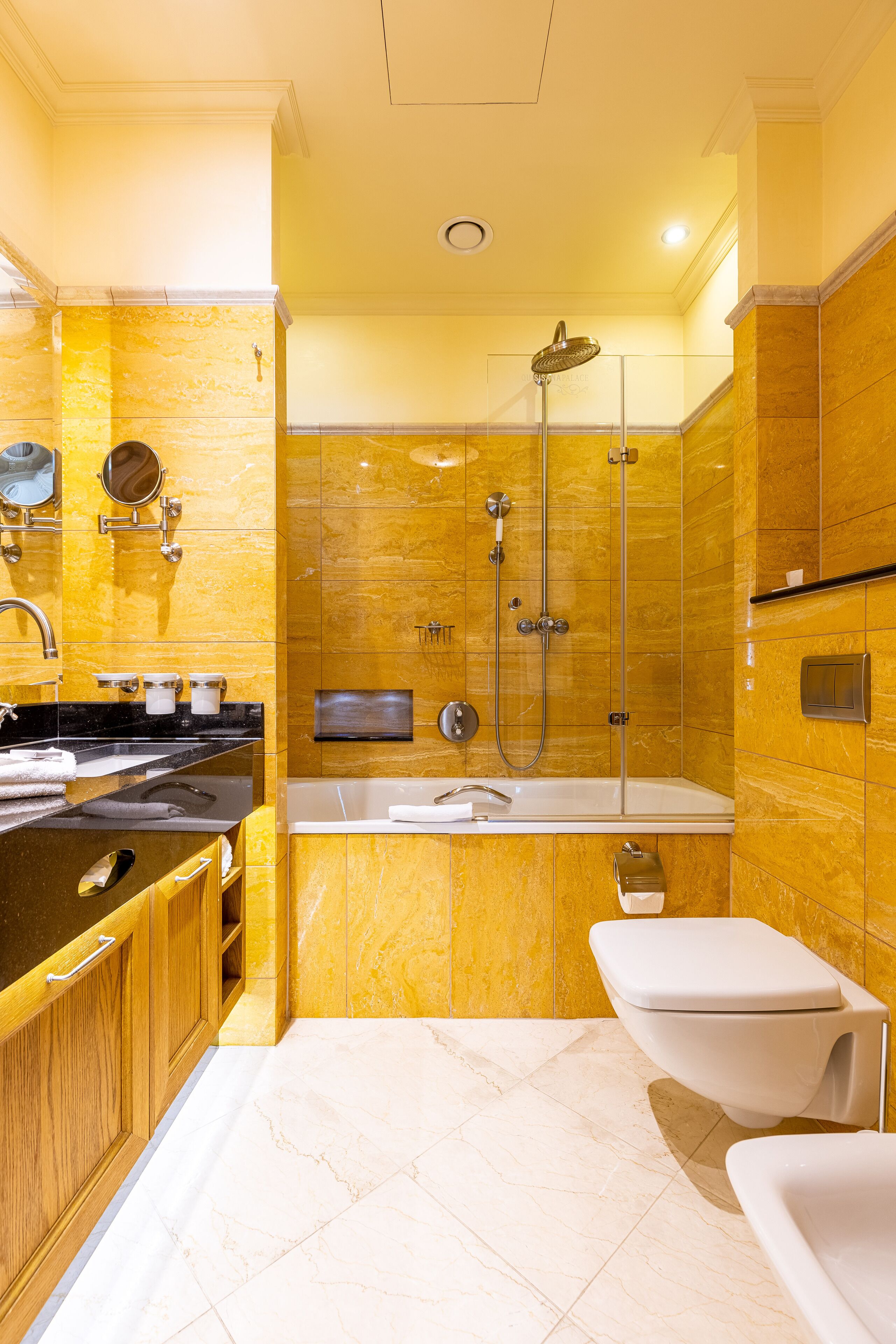 Un baño moderno con lavamanos de superficie negra, inodoro blanco y zona de ducha con mampara de vidrio.