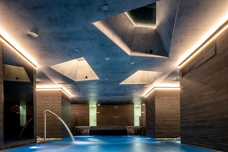 Una piscina techada, sillones reclinables de piscina. Grandhotel Pupp