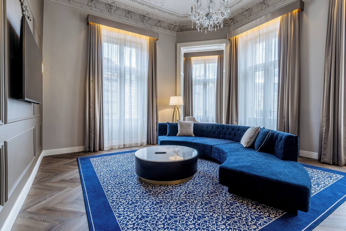 Uma sala de estar moderna com um sofá modular azul, uma mesa de centro redonda e um tapete estampado.