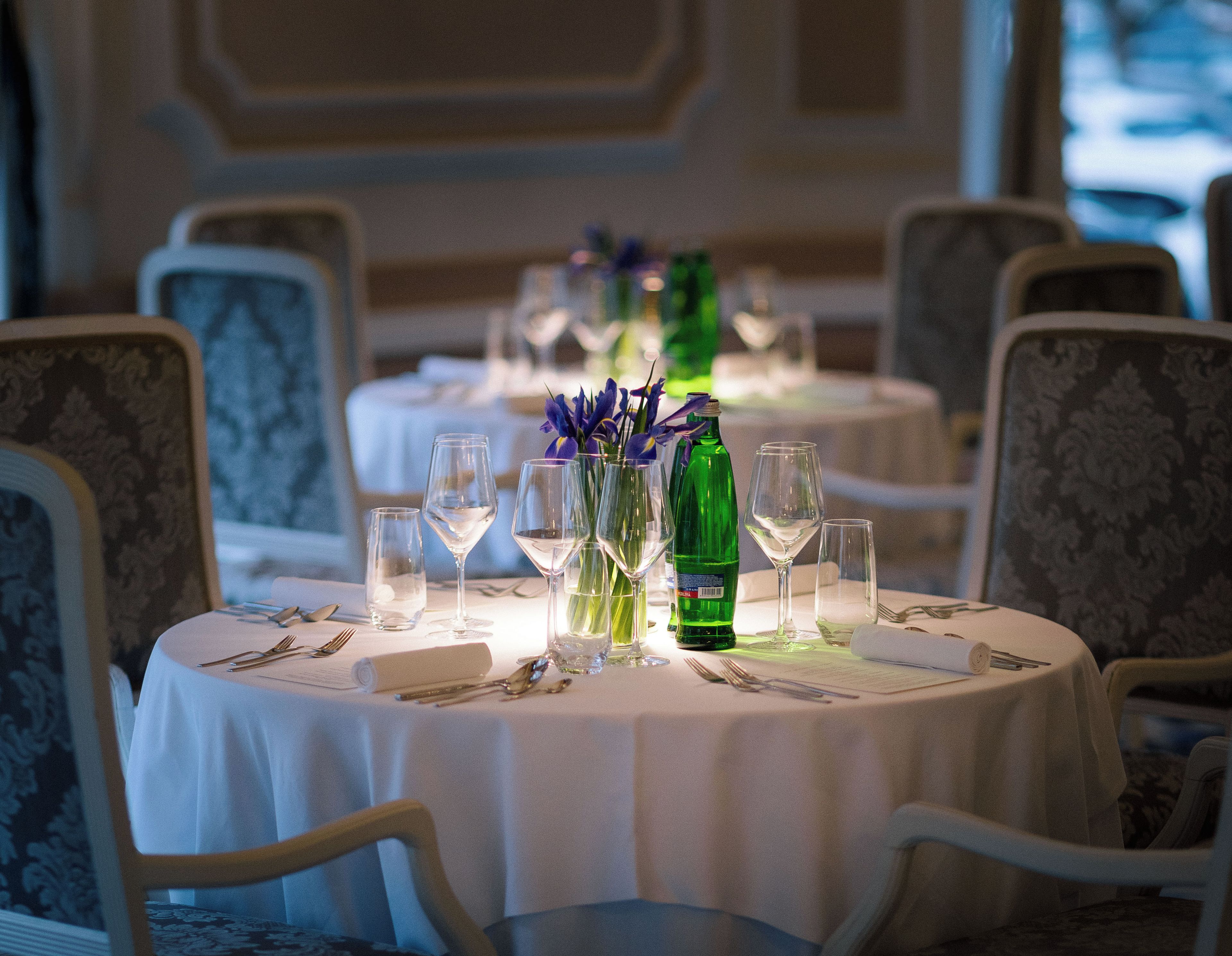 Une table à manger dressée avec plusieurs verres, une bouteille et un vase rempli de fleurs.