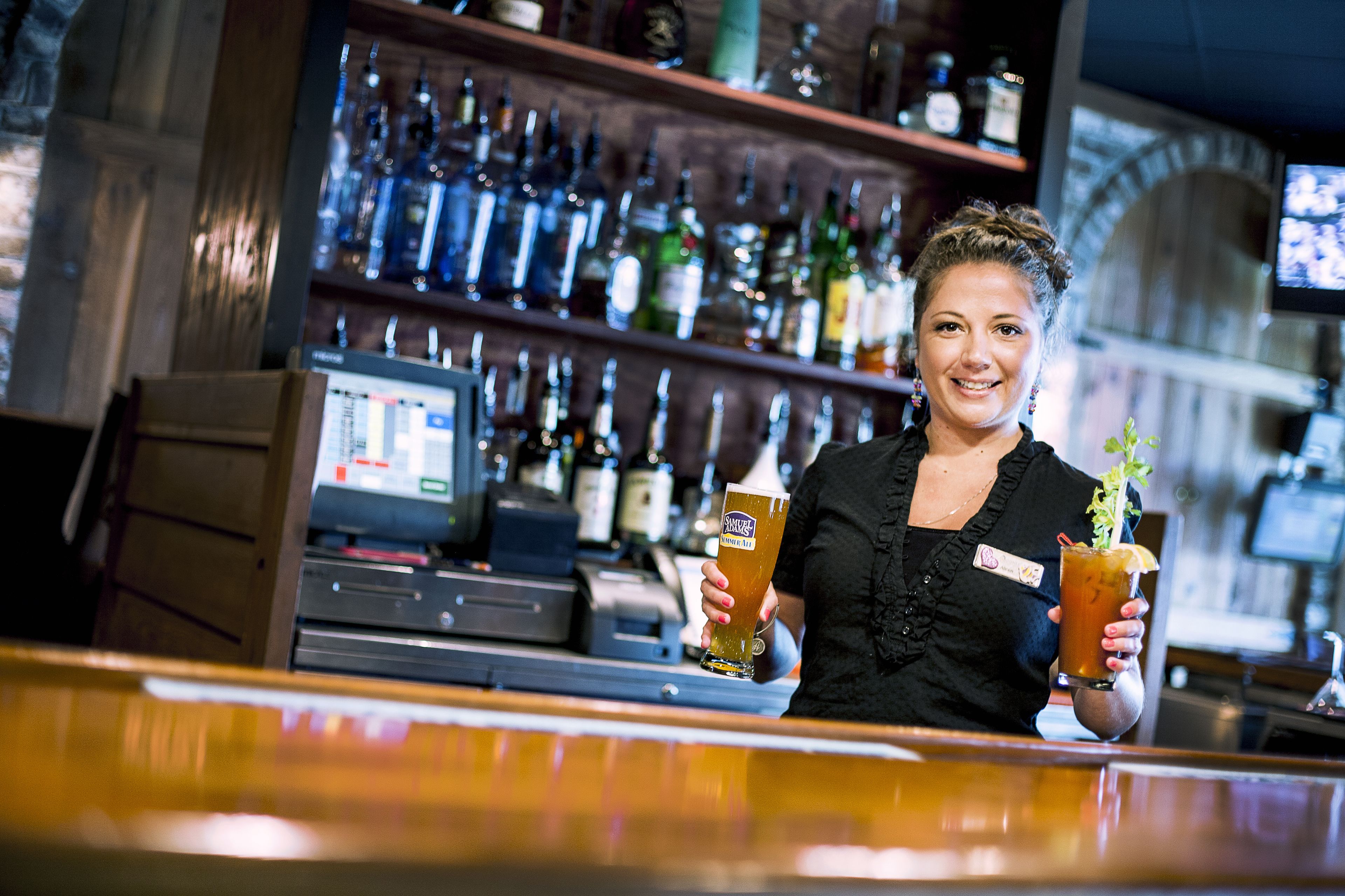 A bar with shelves of bottles and a computer monitor.