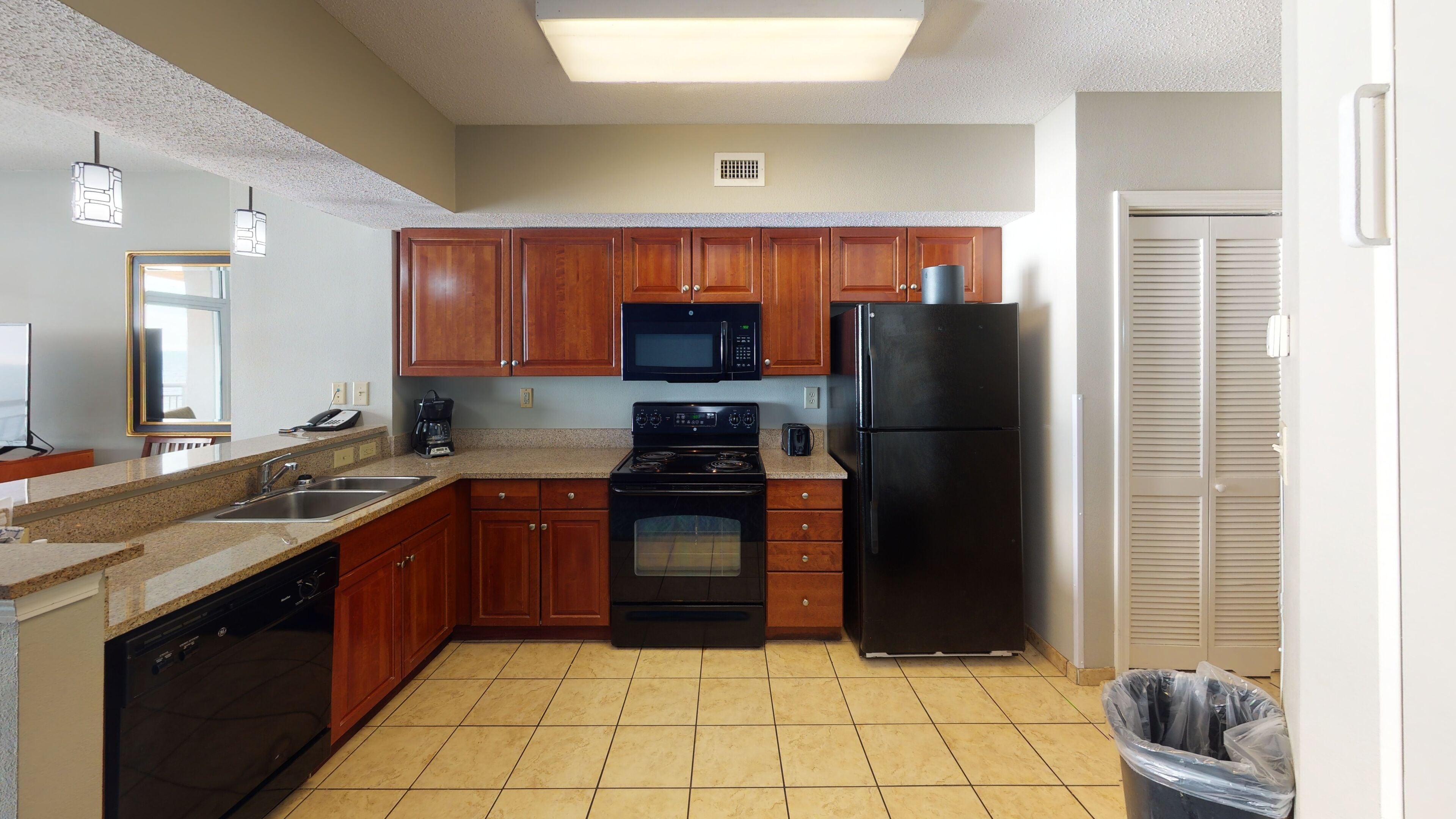 A kitchen with wooden cabinets, a black refrigerator, a microwave, an oven, and a dishwasher.