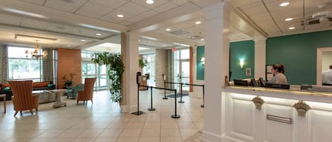 Un hall d’hôtel comprenant un comptoir d’accueil, un espace salon et une grande fenêtre.