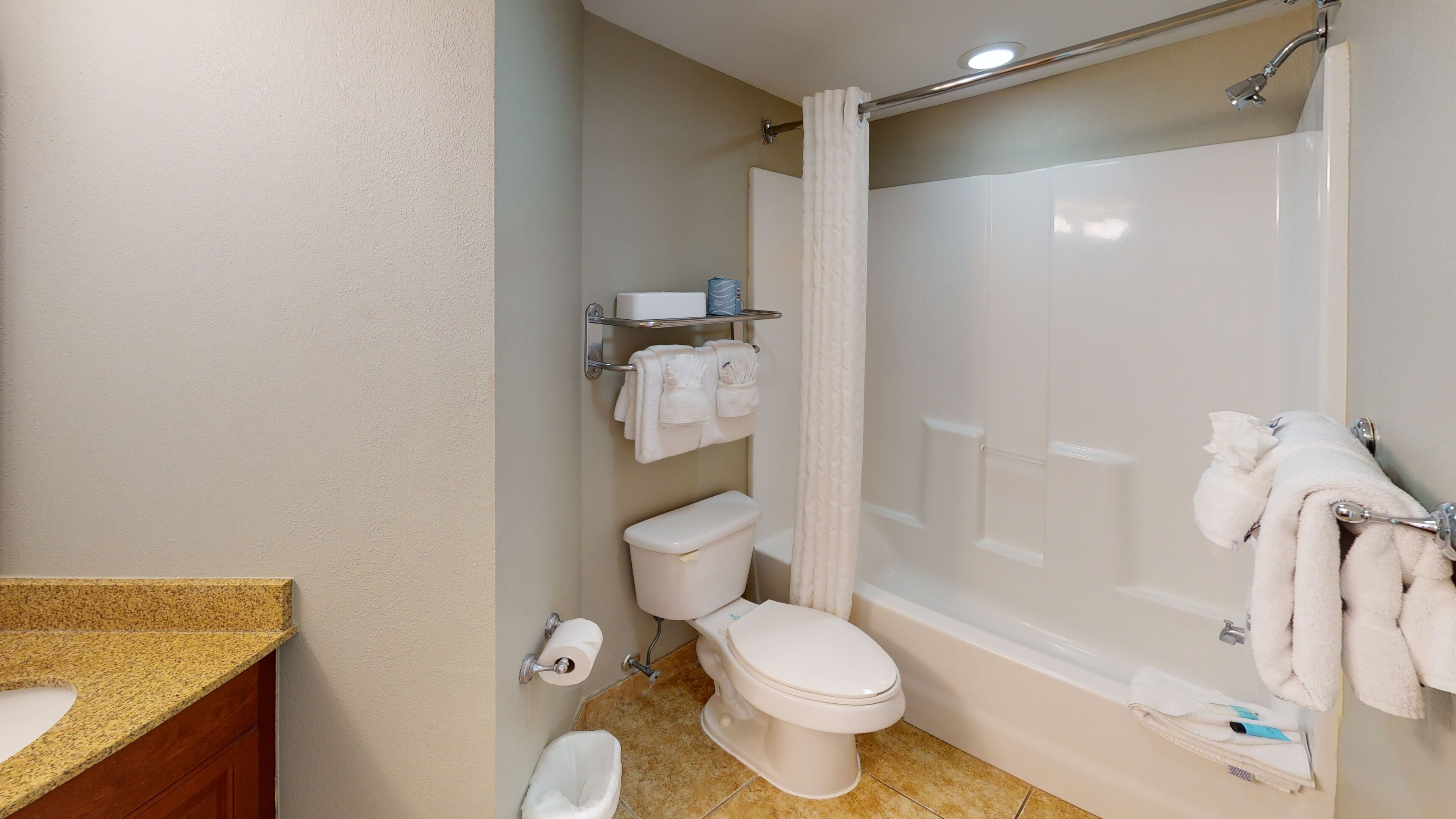 A bathroom with a toilet, sink, and bathtub. There are towels hanging on the wall and a shower curtain.