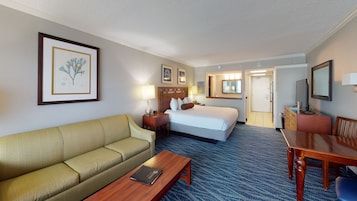 Una habitación de hotel con cama, sofá, escritorio y mesa de comedor.