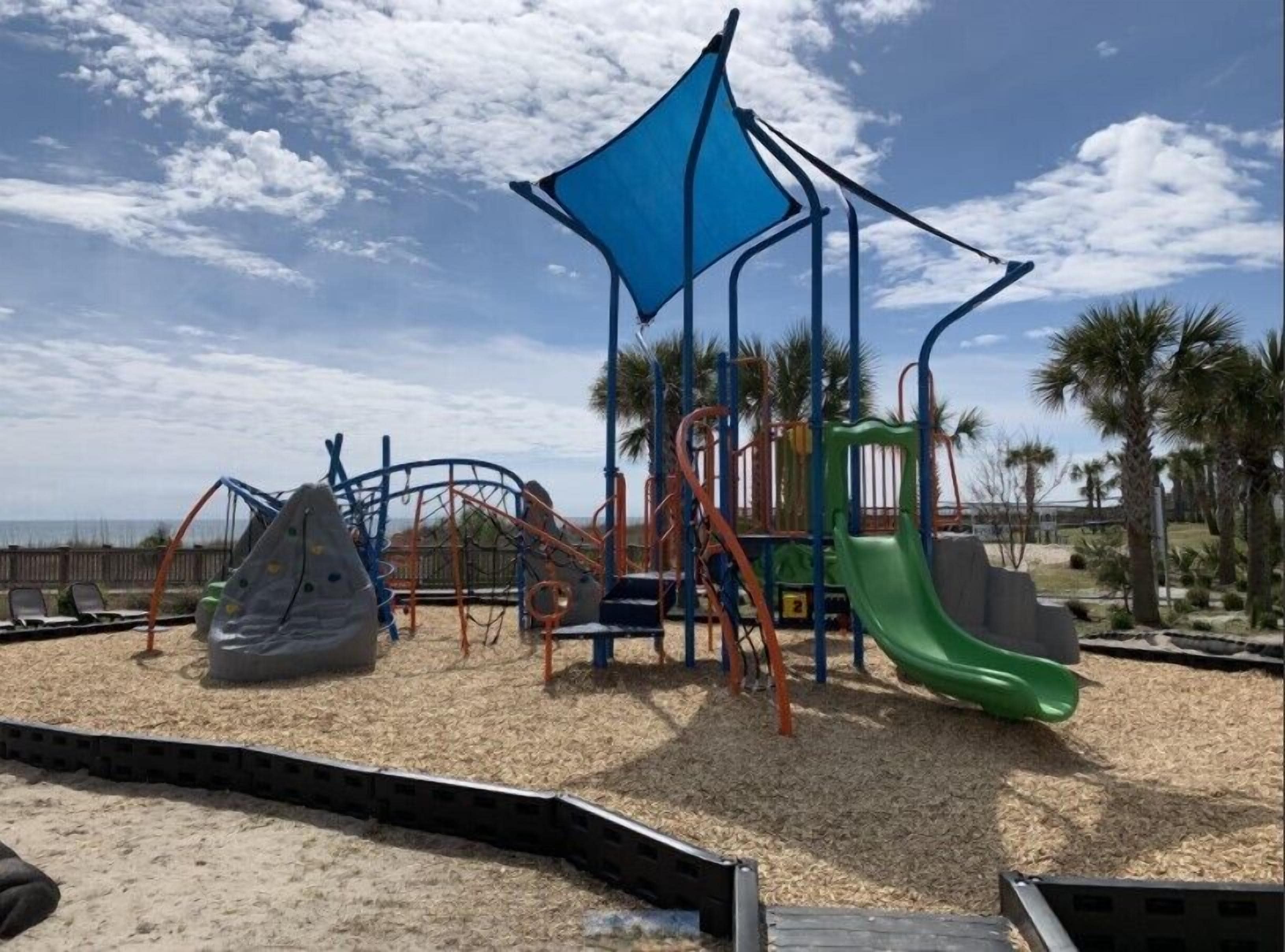 A playground with climbing structures, slides, and a shaded area.