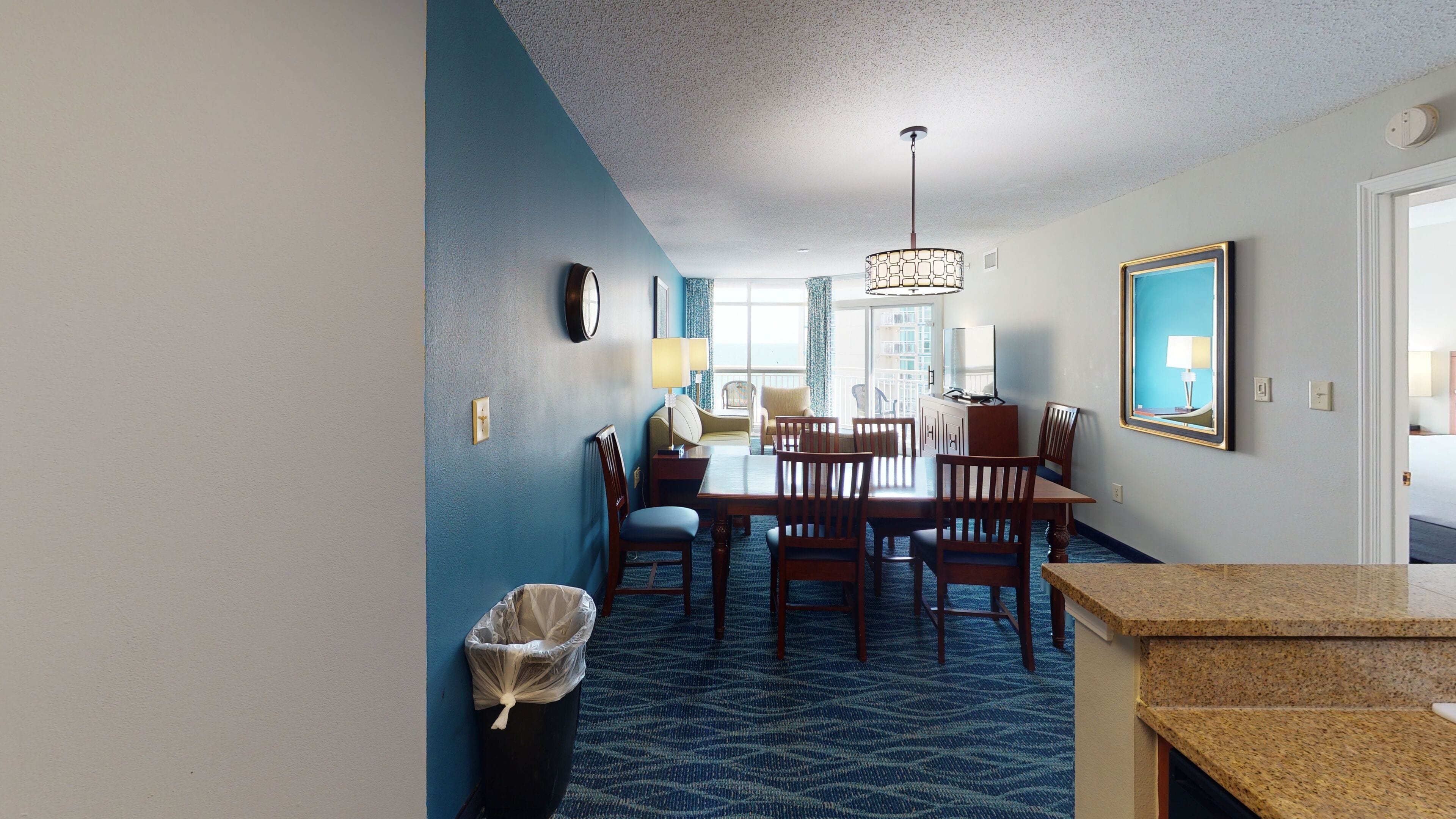 Habitación de hotel con zona de comedor, un ventanal grande y vistas a la ciudad.