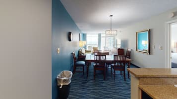 Habitación de hotel con zona de comedor, un ventanal grande y vistas a la ciudad.