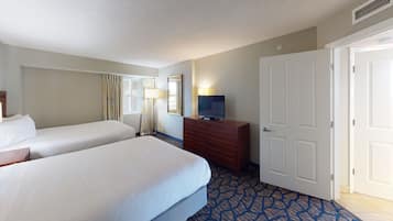 Une chambre d’hôtel avec deux lits, une commode, un téléviseur et une porte.