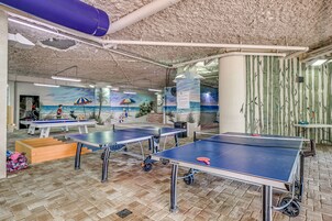 A room with ping pong tables, a mural, and bamboo-patterned walls.