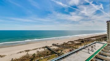 A beach view with a parking area and a building in the foreground.