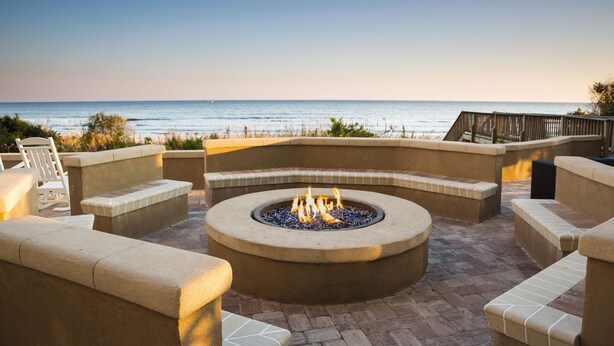 A fire pit surrounded by stone seating, overlooking a beach. - Club Wyndham Ocean Boulevard (North Myrtle Beach)