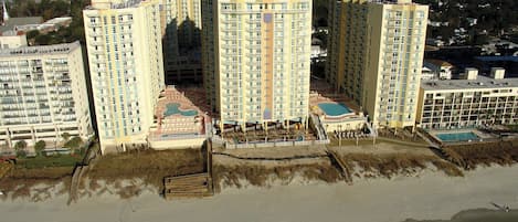 Ein Hochhaus-Hotel mit mehreren Balkonen, einem Poolbereich und Blick auf den Strand.
