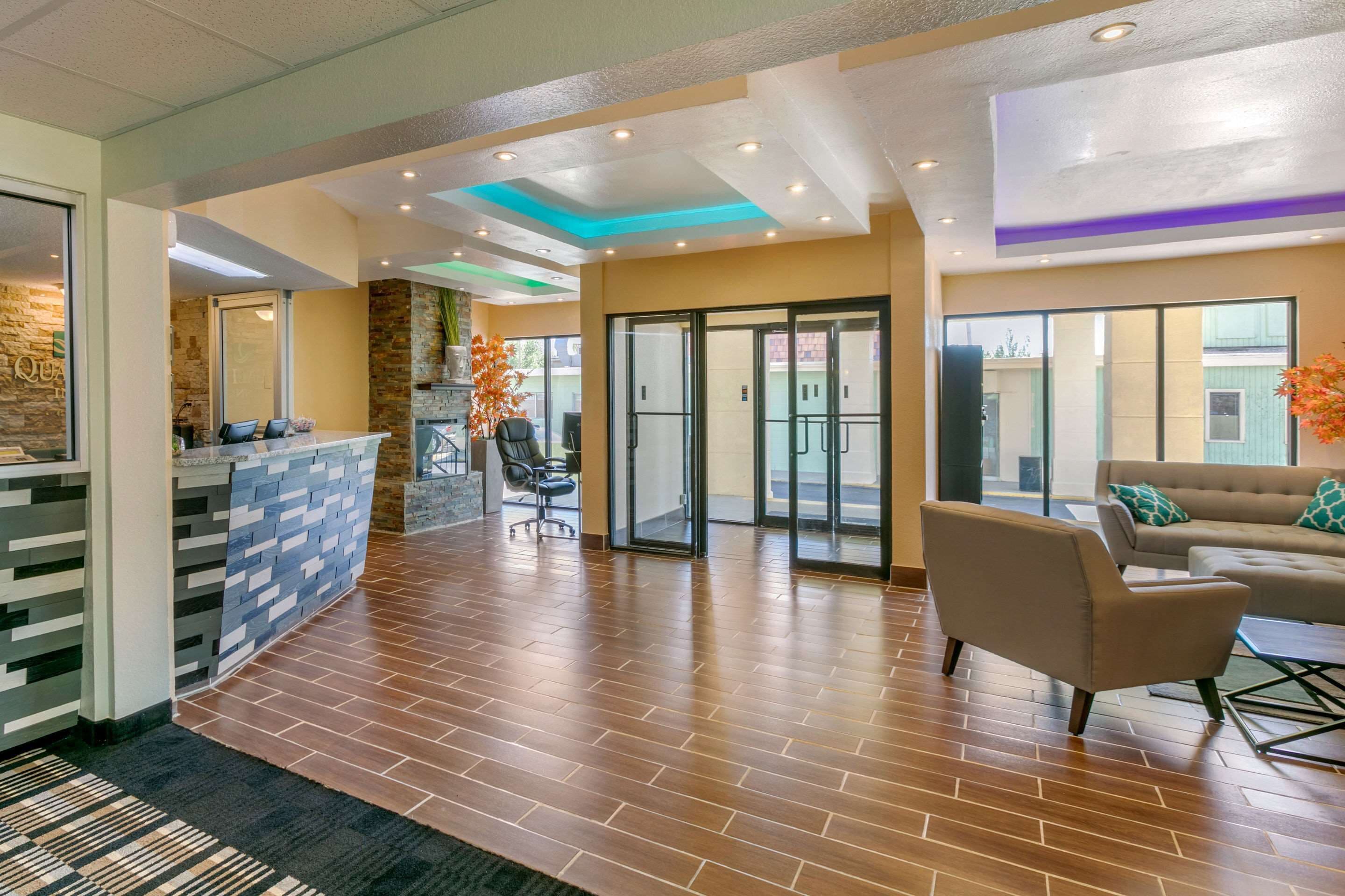 A reception area with a stone wall, a reception desk, a seating area with a sofa and chairs, and a glass door leading outside.