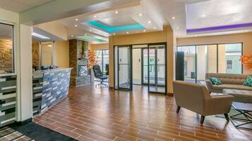 A reception area with a stone wall, a reception desk, a seating area with a sofa and chairs, and a glass door leading outside.