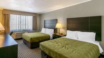 A hotel room with two beds, a desk, and a window with curtains.