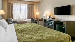A hotel room with a bed, desk, chair, TV, and a window with curtains. - Quality Inn Rawlins I-80 (Rawlins)