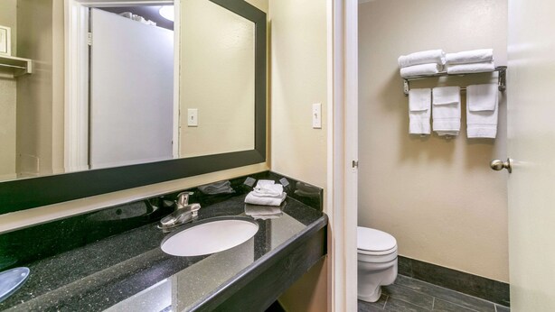 A bathroom with a black granite sink, a white toilet, and a towel rack with folded towels. - Quality Inn Rawlins I-80 (Rawlins)