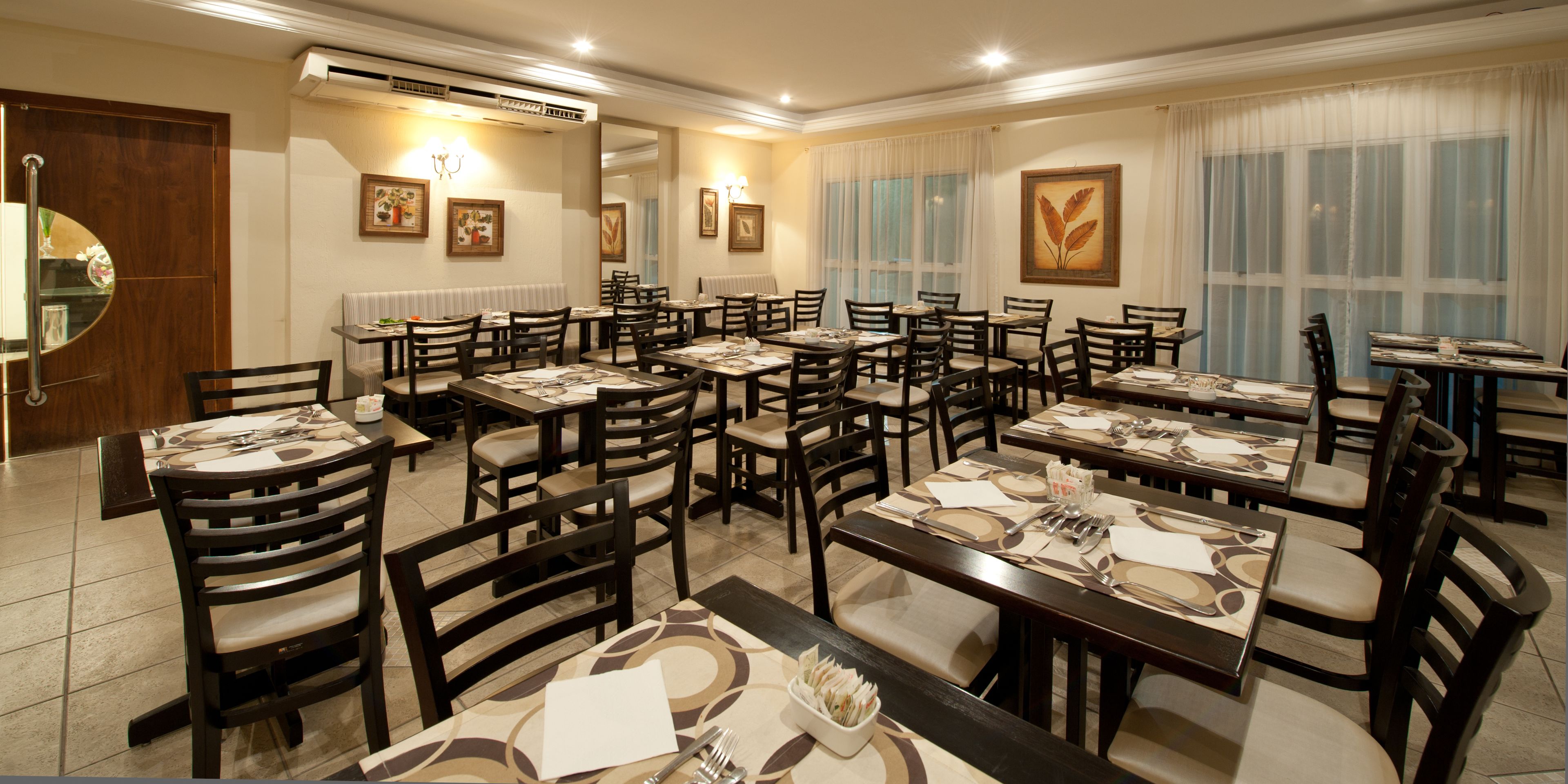 A dining area with multiple tables and chairs, arranged in a spacious layout.