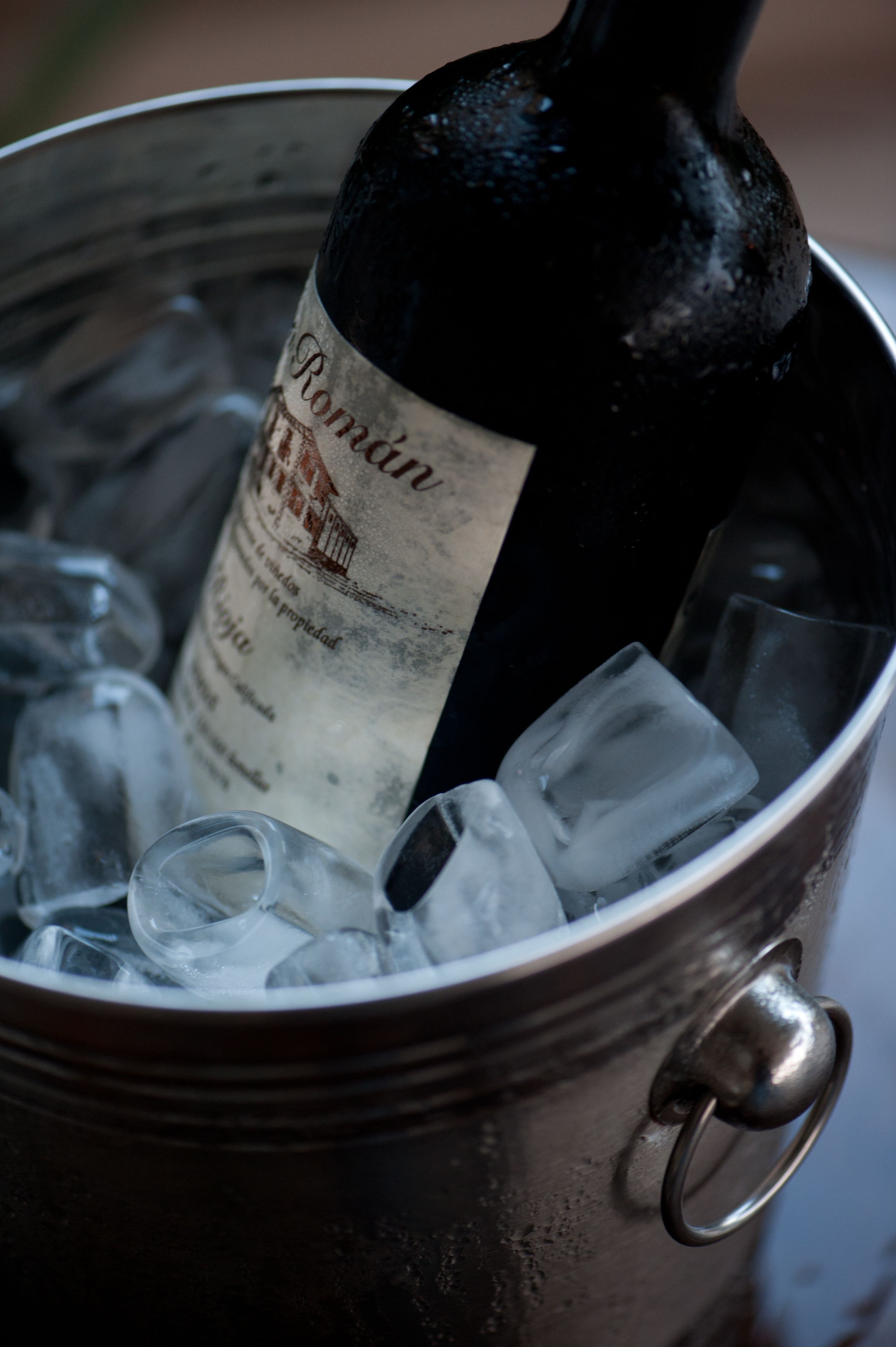 Uma garrafa de vinho Romantín em um balde de metal com cubos de gelo.