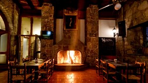 Un restaurante con chimenea de piedra, mesas y sillas de madera.