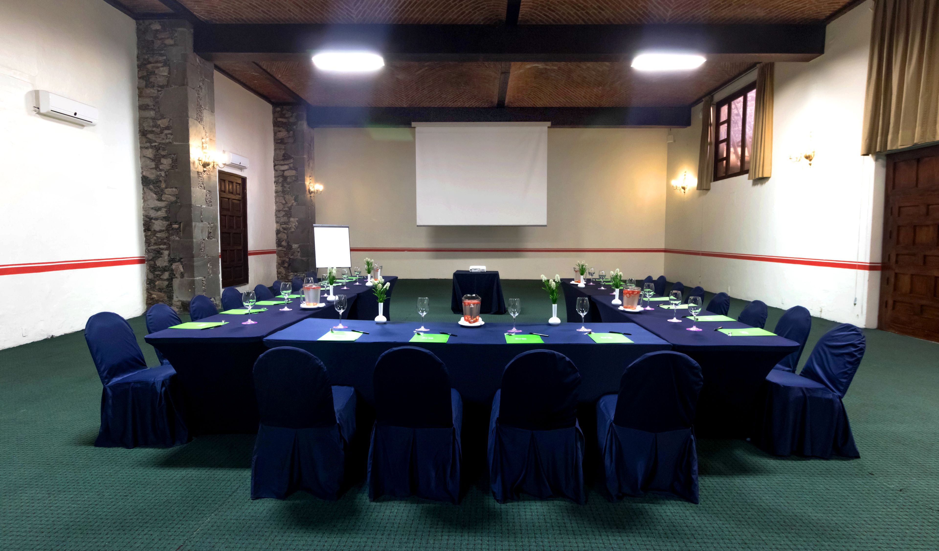 A conference room with a long table, chairs, and a projector screen.