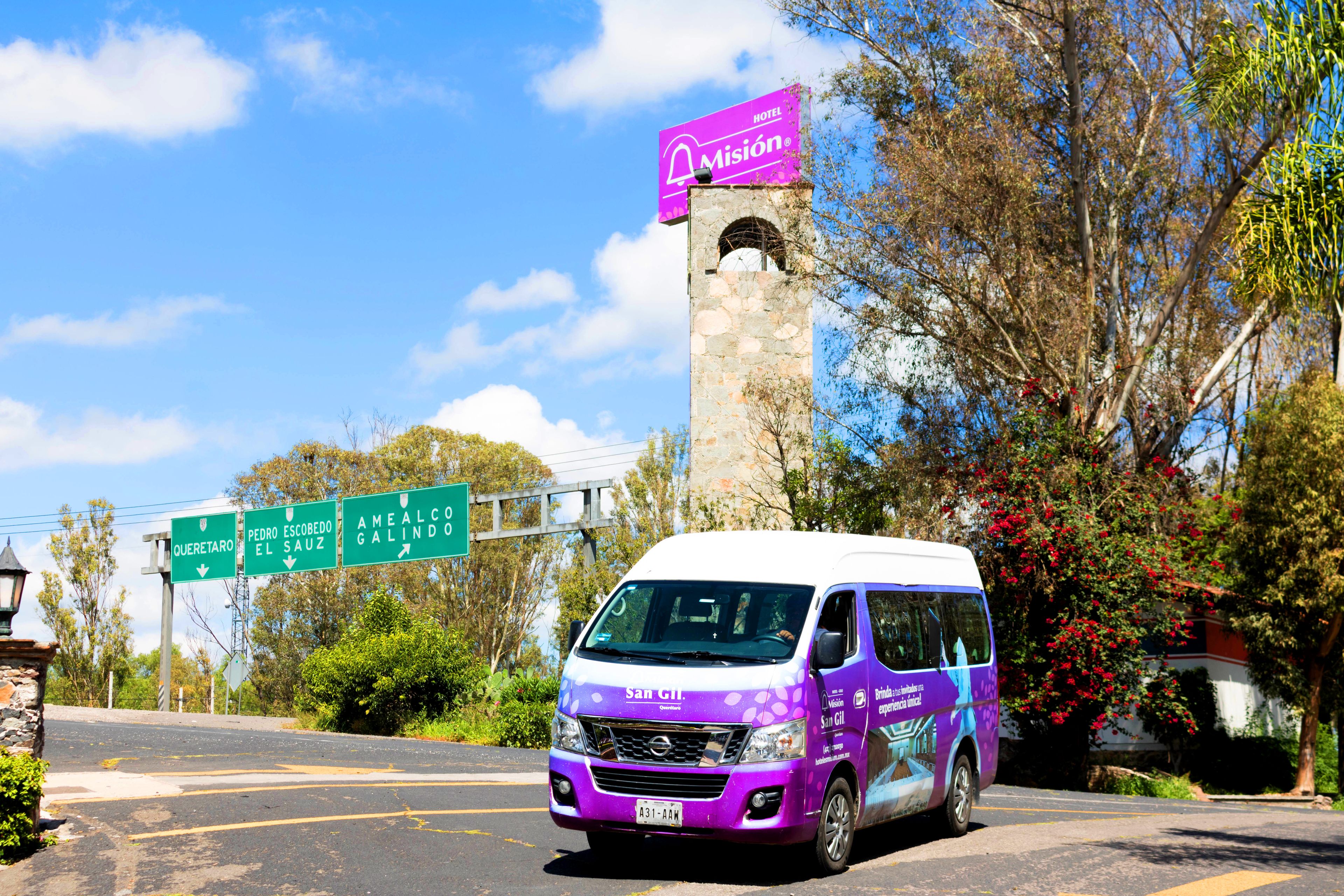 A purple van parked in front of a hotel with a signboard above it.