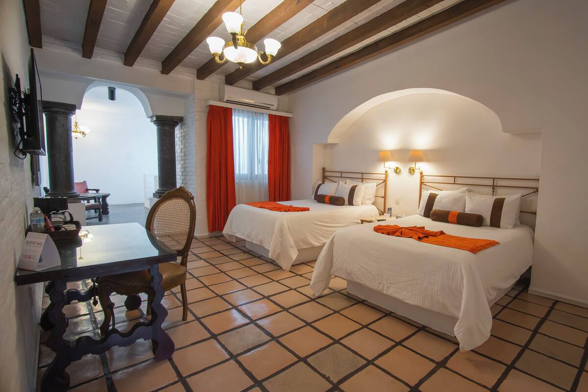 Una habitación de hotel con dos camas, una mesa de comedor y una silla.