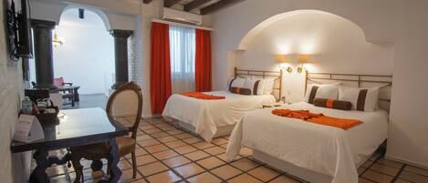 A hotel room with two beds, a dining table, and a chair.