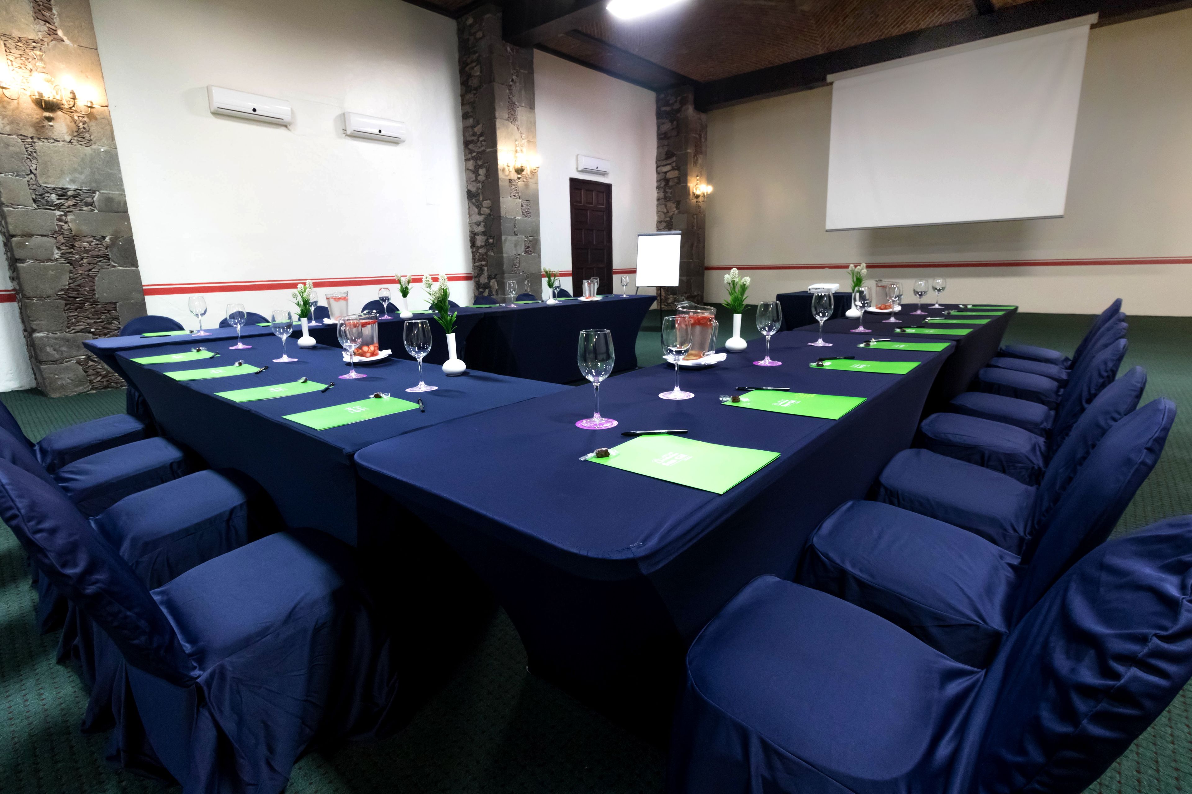 A conference room with a long table set for a meeting, surrounded by chairs.