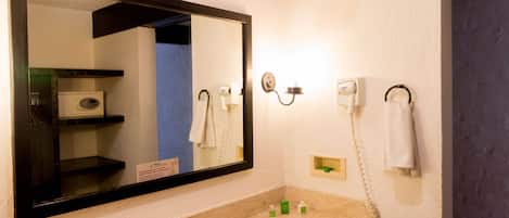 A bathroom with a large mirror, a sink, a hairdryer, and a towel rack.