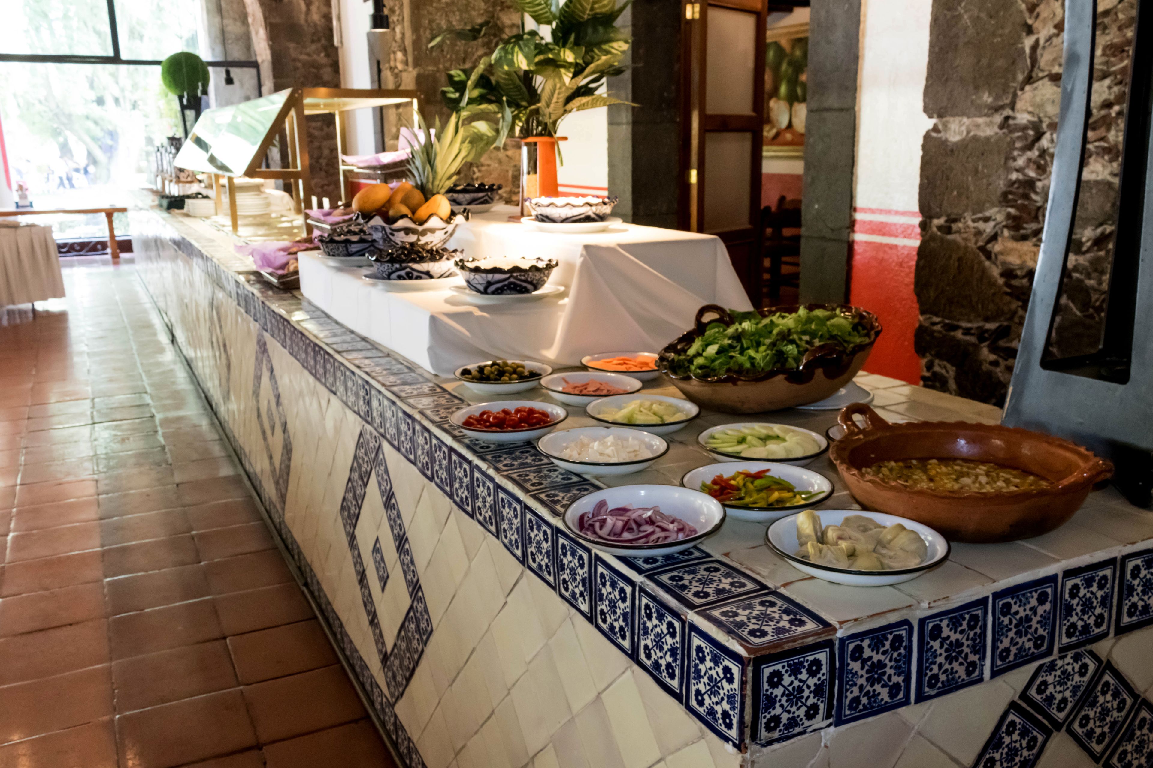 Una taula de buffet amb diversos plats i una planta en test.
