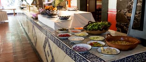 Una mesa de buffet con diversos alimentos y una planta en maceta.