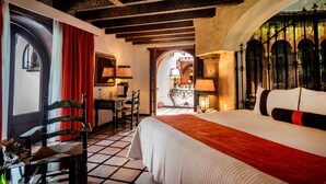 Habitación de hotel con una cama grande, un escritorio y una silla. Cuenta con una ventana con cortinas, una puerta y vistas al exterior.