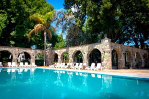 A swimming pool with white lounge chairs and stone arches. - Hotel Misión San Gil (San Juan del Río)