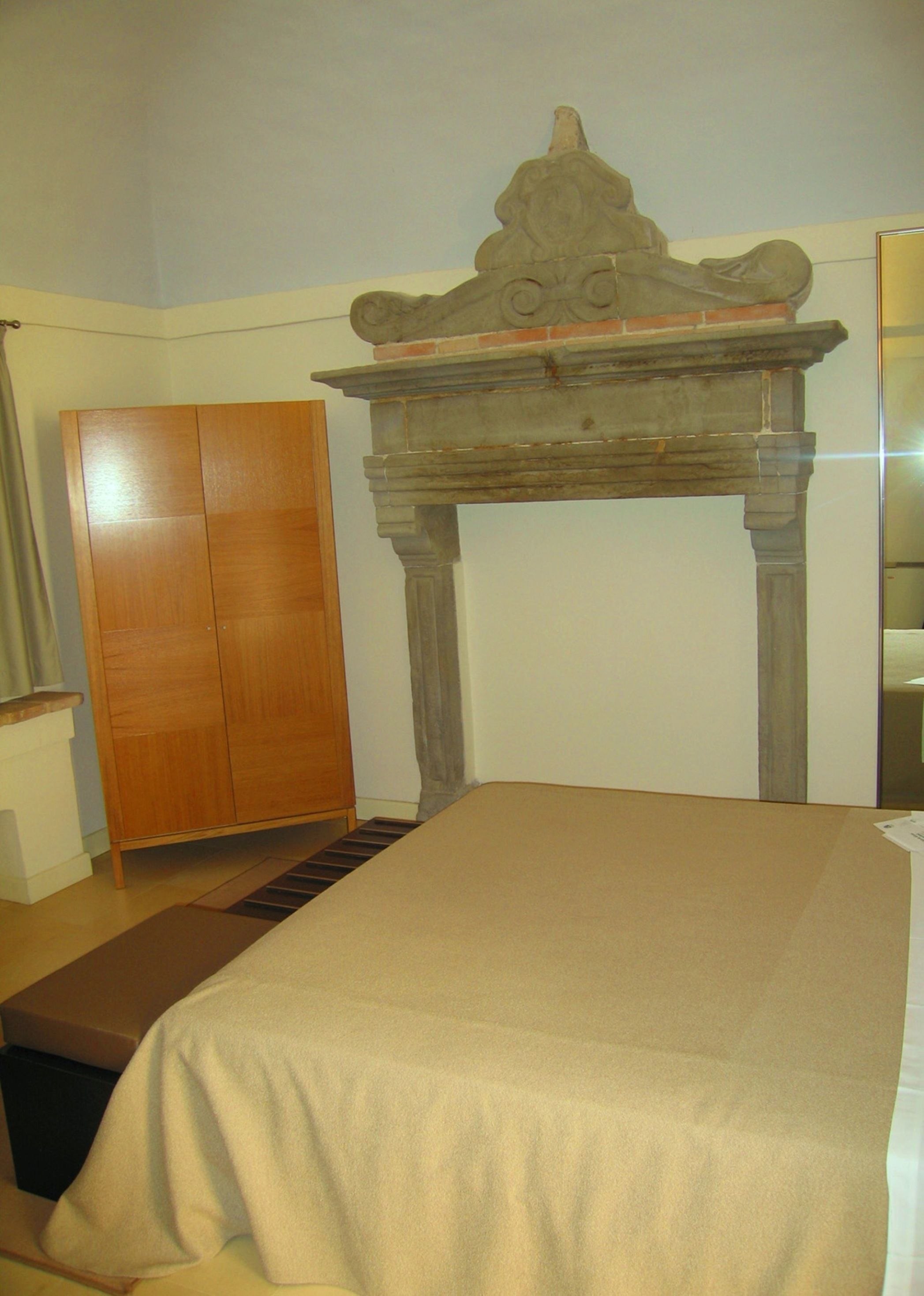 Un dormitorio con cama, armario de madera y chimenea de piedra.