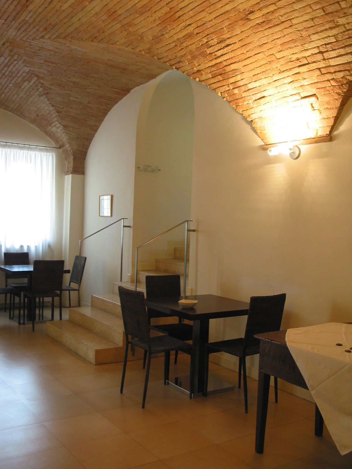A dining area with a brick ceiling, a staircase, and a table with chairs.